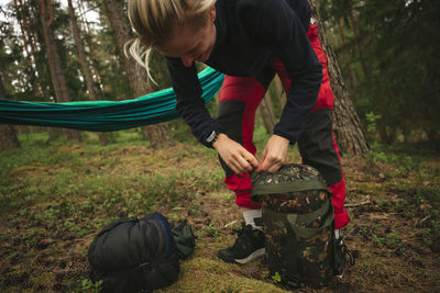 Female hiker packing backpack in forest