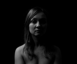 Portrait of a serious young woman over black background