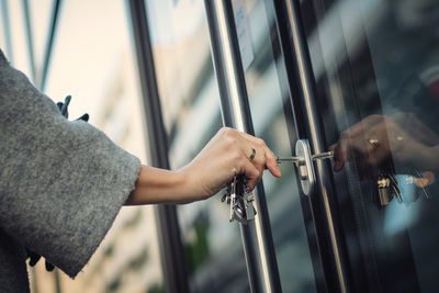 Cropped hand of woman opening door