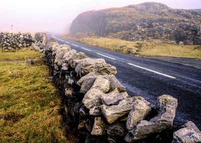 Rocks on road by land against sky