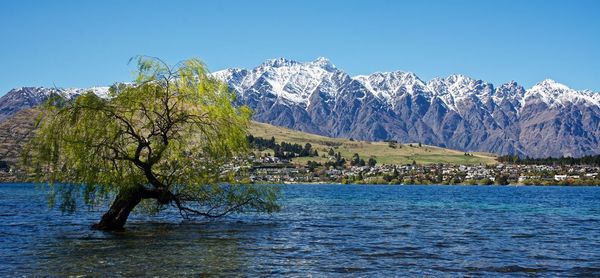 Scenic view of sea and mountains against clear blue sky