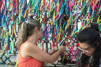 Portrait of two women placing colored ribbons on the church grid. 