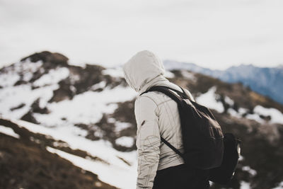 Side view of backpacker wearing hooded jacket on mountain