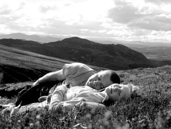 Couple lying on field against sky