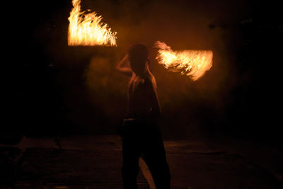 Male fire dancer performing at night