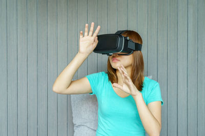 Woman wearing virtual reality simulator against wall