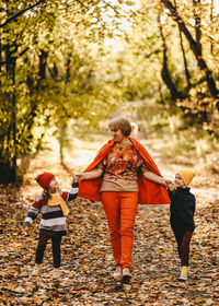 Happy grandmother in warm clothes are walking with their grandchildren in the autumn forest outdoors