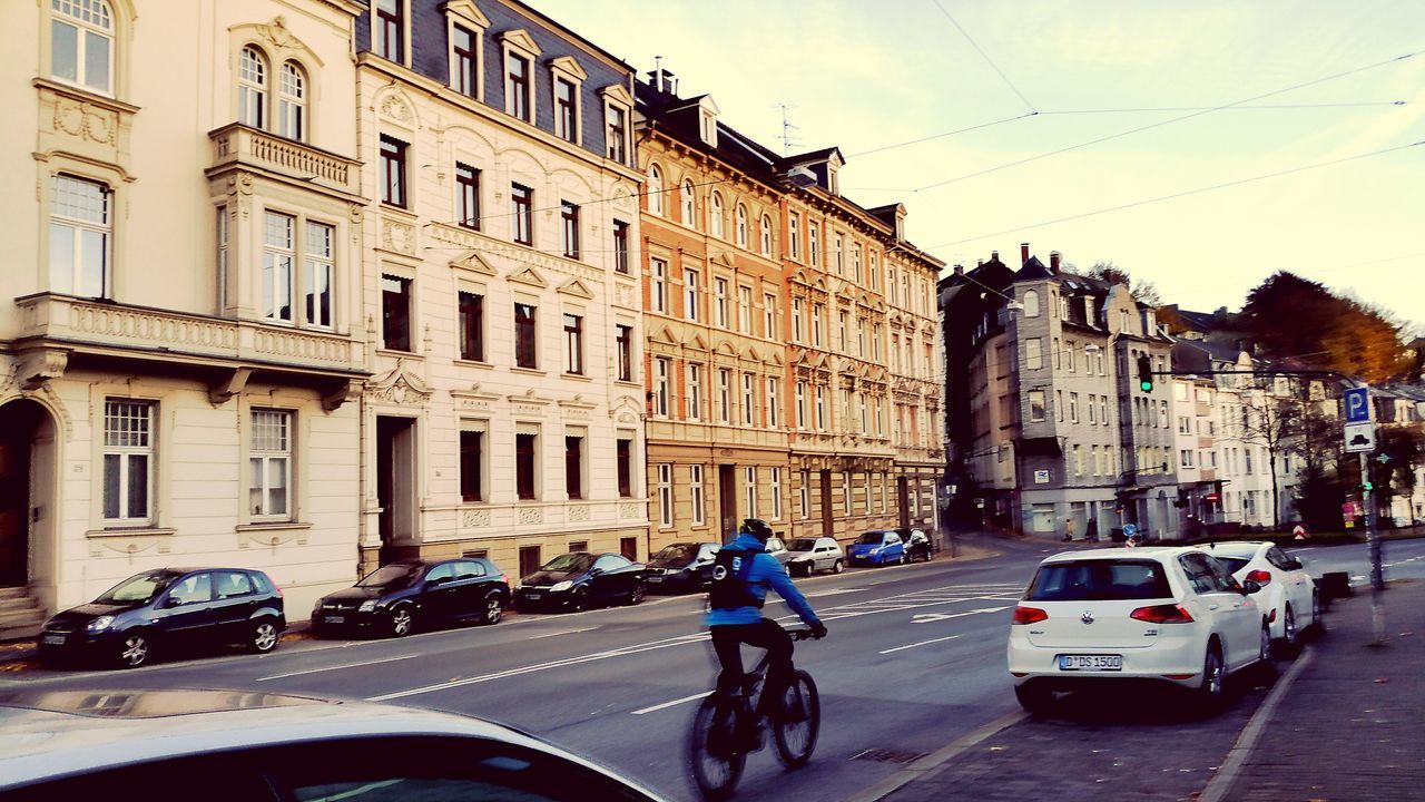 building exterior, car, architecture, transportation, land vehicle, built structure, mode of transport, street, city, road, city life, city street, walking, on the move, men, travel, incidental people, building, traffic