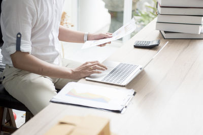 Midsection of woman using laptop on table