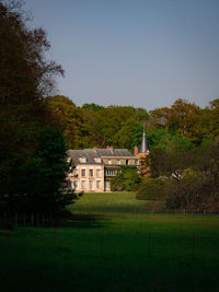 House on field by building against sky