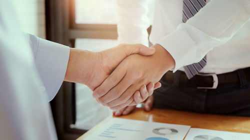 Midsection of couple holding hands on table