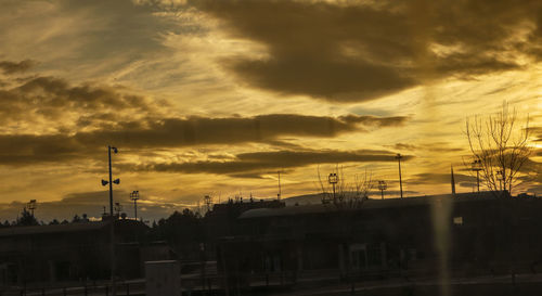 Silhouette buildings against dramatic sky during sunset