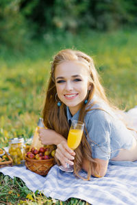 Pretty caucasian young woman with long hair is lying on a blanket in nature on a sunny summer day