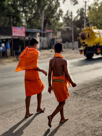 Rear view of men walking on road