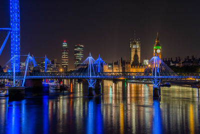 Illuminated hungerford bridge and golden jubilee bridges and houses of parliament in city at night