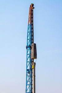 Low angle view of crane against clear blue sky