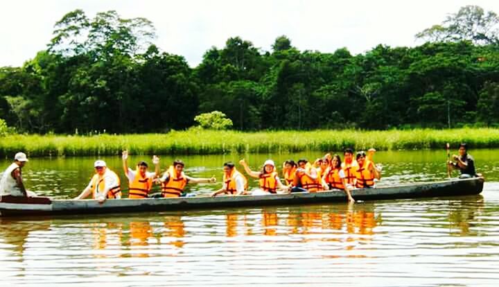 water, tree, lake, men, transportation, food and drink, person, day, waterfront, nautical vessel, outdoors, nature, in a row, large group of people, mode of transport, sky, side by side, relaxation