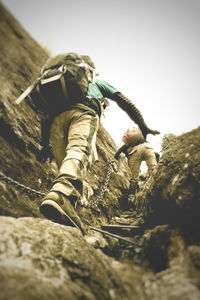 Low angle view of men climbing against sky