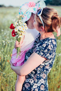 Low angle view of woman carrying daughter holding flower bouquet