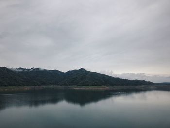 Scenic view of lake by mountains against sky