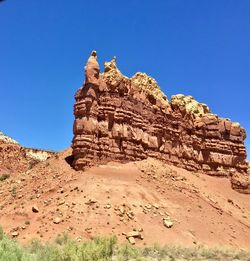 Low angle view of rock formations against clear blue sky