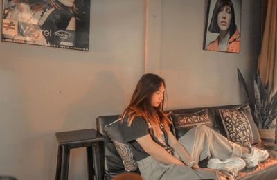 Woman looking away while sitting on chair at home