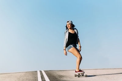 Woman skateboarding against blue sky