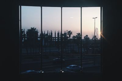 Silhouette trees against sky seen through glass window