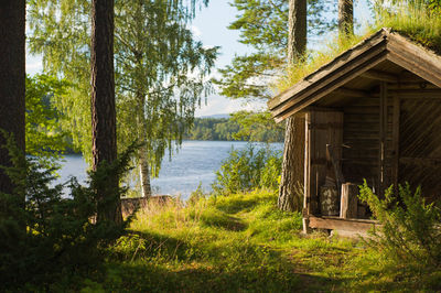 Log cabin by trees against lake