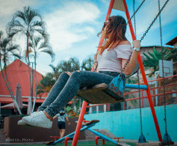 Woman sitting on swing at playground