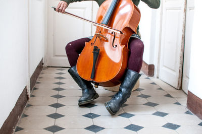 Low section of musician playing double bass in corridor