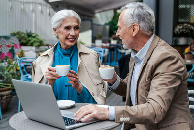 Man and woman using phone while sitting on table