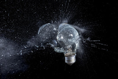 Close-up of illuminated light bulb against black background