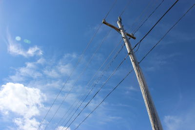 Low angle view of electricity pole against cloudy sky