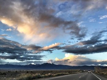 Country road against cloudy sky