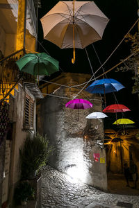 Illuminated lanterns hanging by building during rainy season