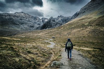 Rear view of man walking on snowcapped mountain