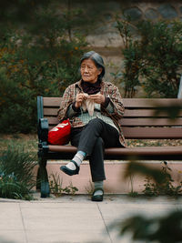 Elderly woman crocheting on a park bench