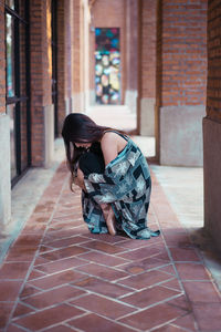 Side view of woman crouching in corridor