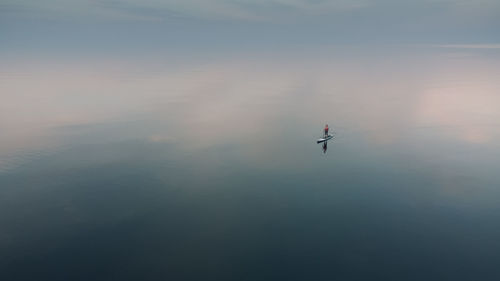 A woman is sailing on a sup board on the mirror surface of the sea. alone with the natural element