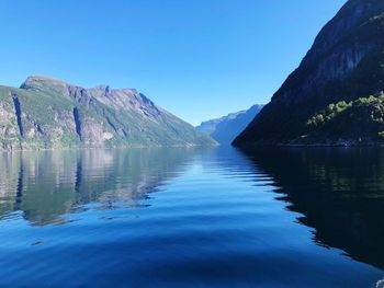 Scenic view of lake and mountains against clear blue sky