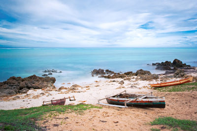 Scenic view of beach against sky, three canoe and reef 