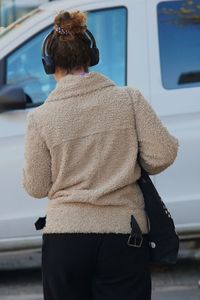 Rear view of woman listening music while walking on road