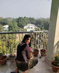 Portrait of woman sitting on railing against plants