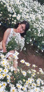 Portrait of beautiful woman against white flowering plants