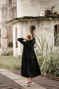 Rear view of young woman standing against building