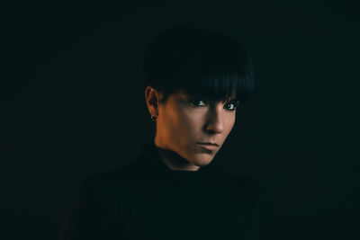 Portrait of young man against black background