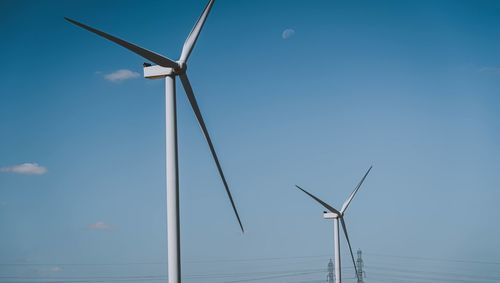 Low angle view of wind turbines against sky