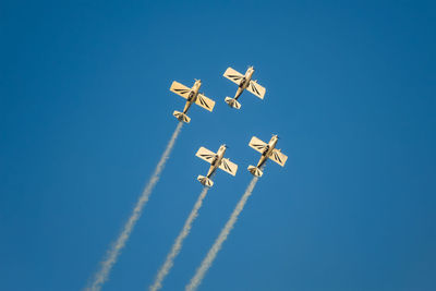 Low angle view of airshow against clear blue sky