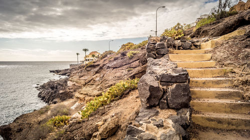 Stone wall by sea against sky